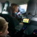 Ett barn tittar på mobil under bilresan. Mobilen hänger i en flexibel mobilhållare runt nackstödet på framsätet.