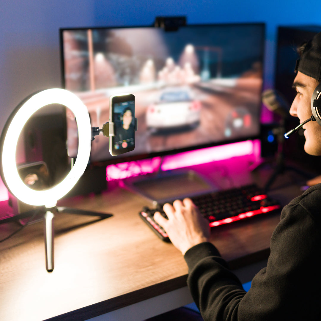 Kille filmar sig själv när han spelar datorspel, framför en ring light med mobilhållare