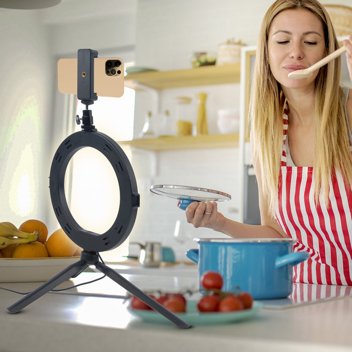 Kvinna spelar in en film när hon lagar mat framför en ring light med mobilhållare